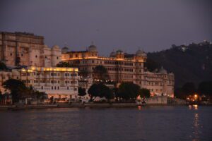 Udaipur City Palace lit up at dusk above Lake Pichola, Rajasthan