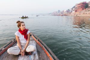 Traveller in a wooden boat on the Ganges below the ghats at Varanasi