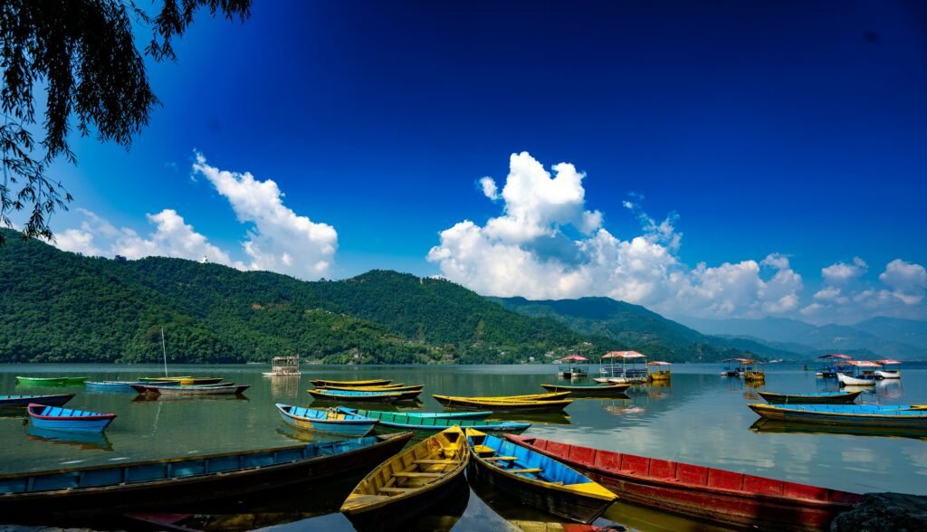 Colorful wooden boats on Phewa Lake in Pokhara, Nepal, with World Peace Pagoda on the hilltop