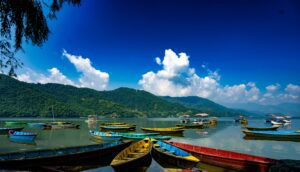 Colorful wooden boats on Phewa Lake in Pokhara, Nepal, with World Peace Pagoda on the hilltop