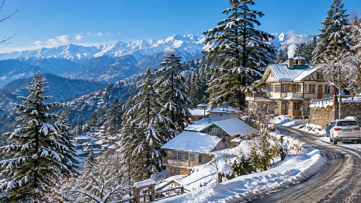 Fresh snow on deodar trees and hillside houses near Shimla with Himalayan peaks in winter