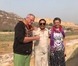 Our travelers enjoying their visit to Amber Fort in Jaipur with their trusted local guide. Mature couple with local Indian guide posing in front of Amber Fort hilltop palace in Jaipur, Rajasthan