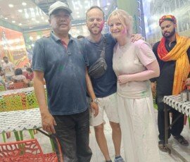 Our travelers experiencing the joyous Holi festival—India's most vibrant celebration of colors. Western tourists covered in colored powder celebrating Holi festival of colors with local guide in India