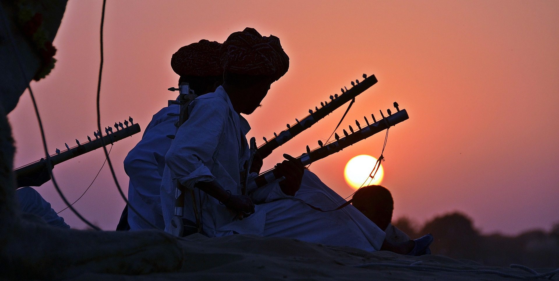 Rajasthani folk musicians with ravanhatha fiddles at sunset in the dunes of Pushkar